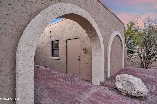 exterior entry at dusk featuring a patio area