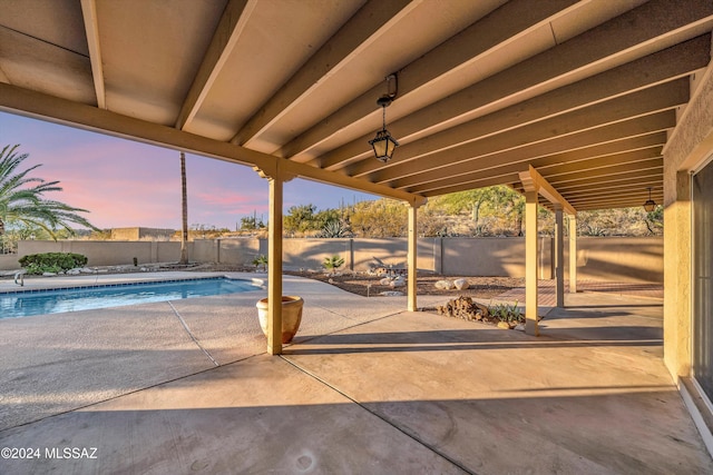 patio terrace at dusk with a fenced in pool