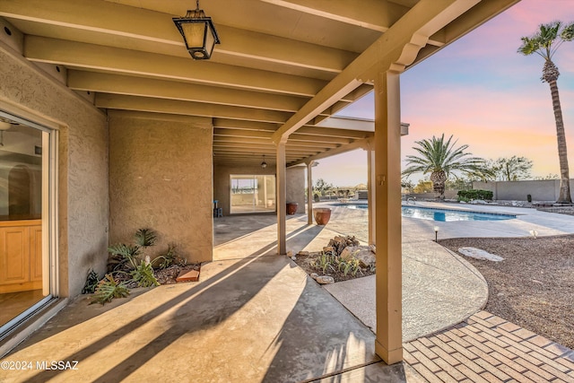 patio terrace at dusk with a fenced in pool