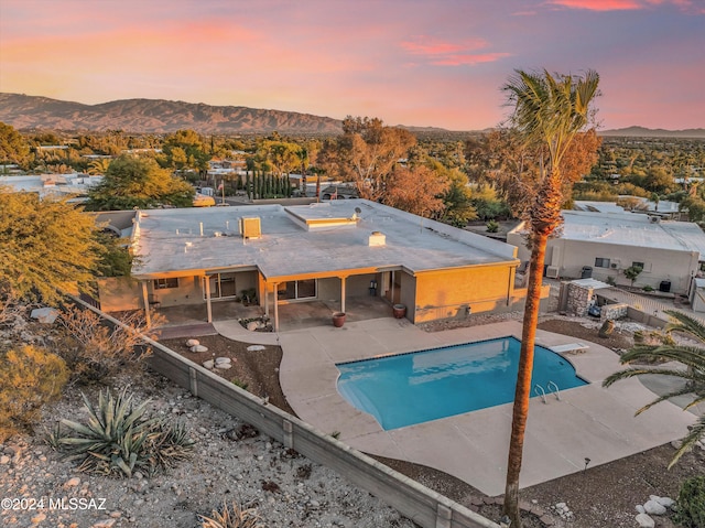 pool at dusk featuring a mountain view and a patio