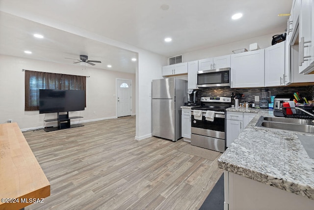 kitchen with white cabinetry, ceiling fan, backsplash, appliances with stainless steel finishes, and light wood-type flooring