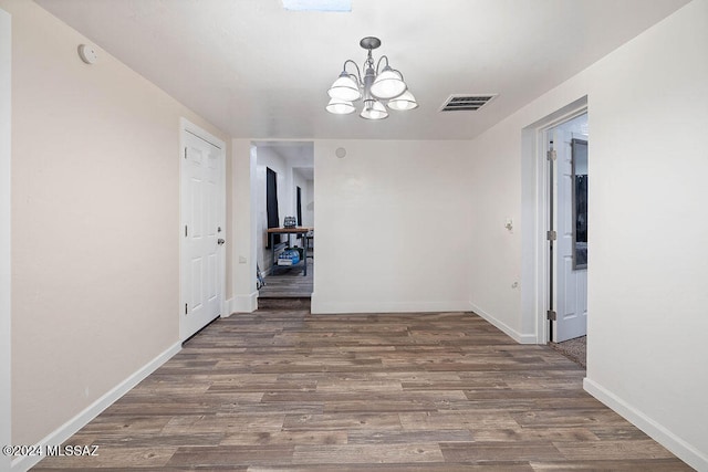 unfurnished dining area featuring a notable chandelier and dark hardwood / wood-style floors