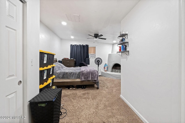 carpeted bedroom with a large fireplace and ceiling fan