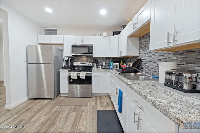 kitchen featuring white cabinets, sink, light wood-type flooring, and stainless steel appliances