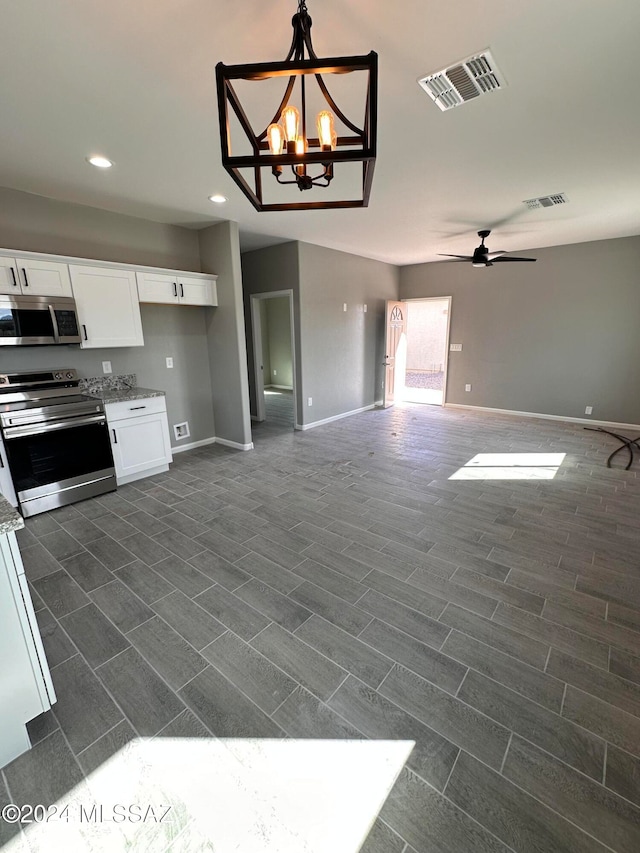 kitchen featuring white cabinetry, appliances with stainless steel finishes, ceiling fan with notable chandelier, dark hardwood / wood-style floors, and hanging light fixtures