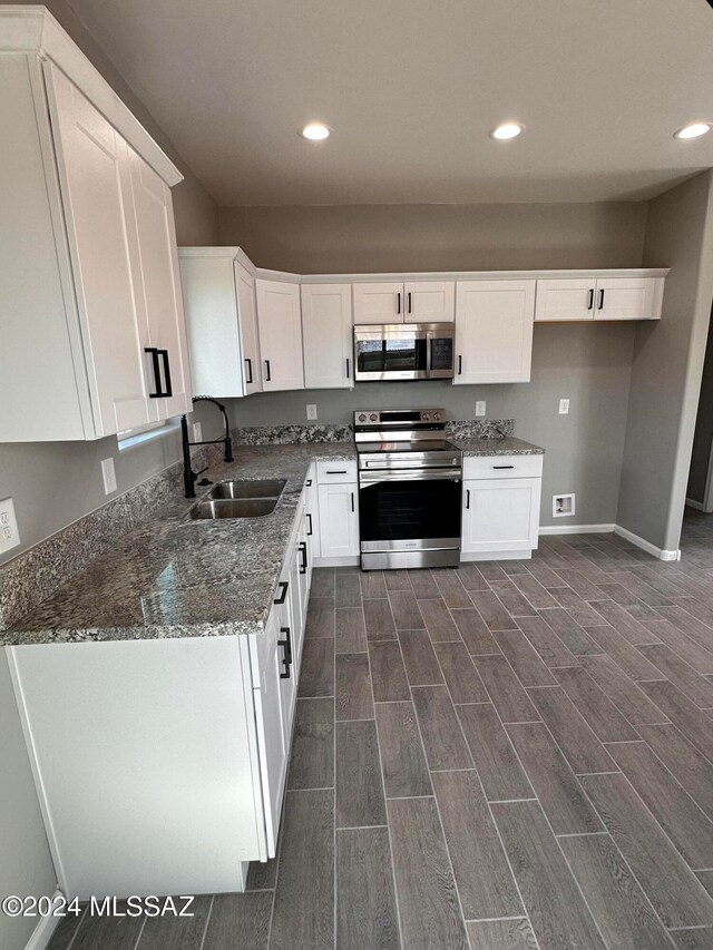 kitchen with white cabinets, appliances with stainless steel finishes, sink, and dark hardwood / wood-style floors