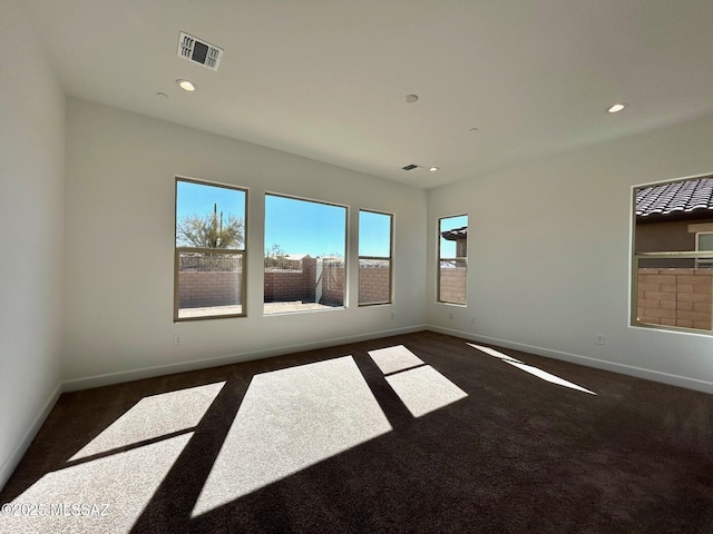 empty room featuring dark colored carpet, recessed lighting, visible vents, and baseboards