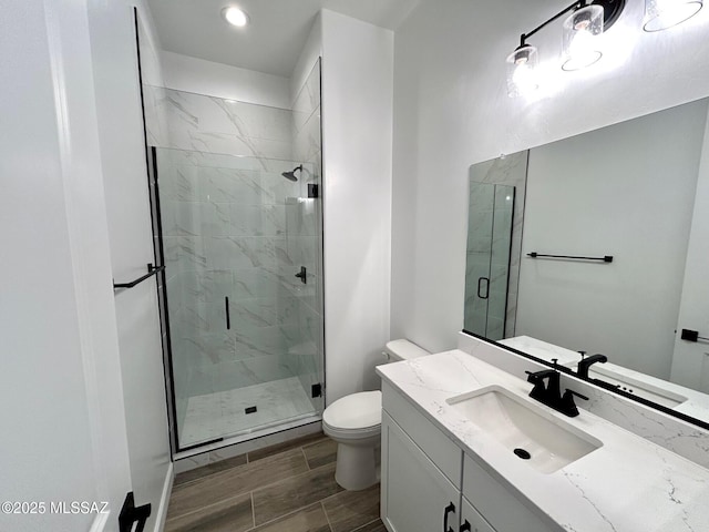 bathroom featuring toilet, a stall shower, vanity, and wood tiled floor