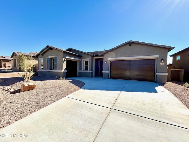 ranch-style home featuring driveway, an attached garage, and stucco siding