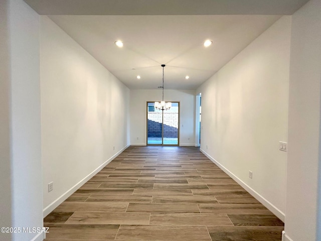 unfurnished dining area featuring recessed lighting, wood finish floors, a notable chandelier, and baseboards