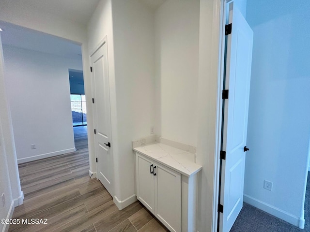 hall featuring light wood-style flooring and baseboards