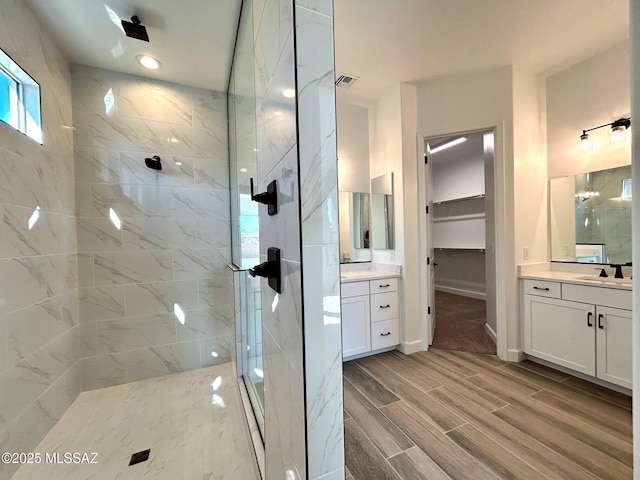 full bath featuring visible vents, a spacious closet, wood tiled floor, a sink, and a shower stall