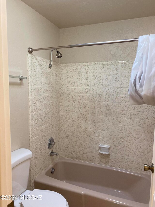 bathroom featuring toilet and tiled shower / bath