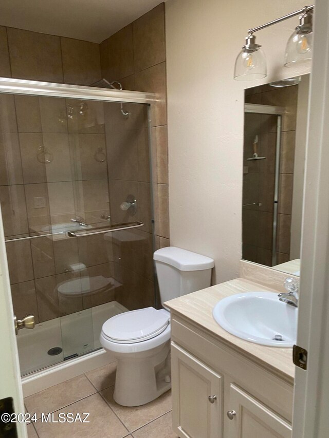 bathroom featuring tile patterned flooring, vanity, a shower with shower door, and toilet