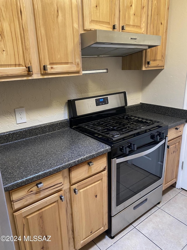 625 S Prudence Rd Unit 209, Tucson, AZ 85710 - kitchen with stainless steel gas range oven, under cabinet range hood, a textured wall, and light tile patterned flooring