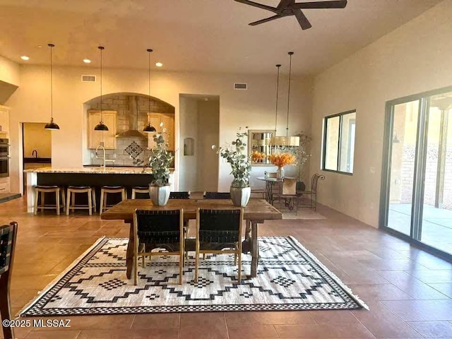 dining area with sink, a towering ceiling, and ceiling fan