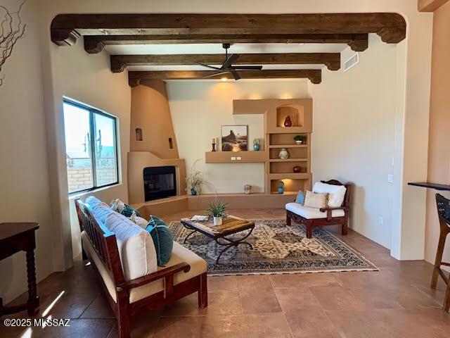 living room with beam ceiling, a large fireplace, and ceiling fan