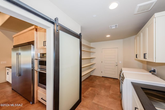 washroom with a barn door and independent washer and dryer