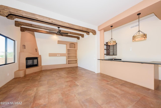 unfurnished living room with ceiling fan, a fireplace, and beamed ceiling