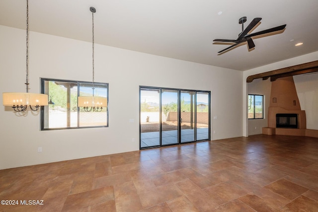 unfurnished living room featuring ceiling fan with notable chandelier and a fireplace