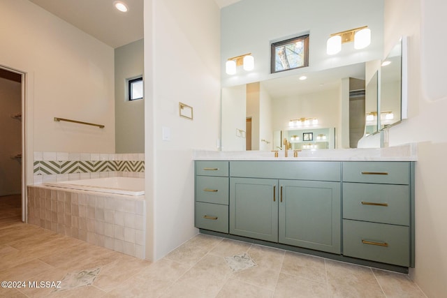 bathroom featuring a relaxing tiled tub, vanity, and tile patterned floors