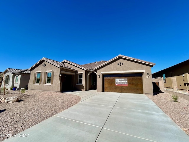 mediterranean / spanish-style home with an attached garage, driveway, a tile roof, and stucco siding