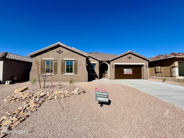 view of front of home featuring concrete driveway, an attached garage, a tile roof, and stucco siding