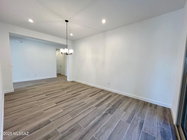 unfurnished dining area with a chandelier, wood finish floors, baseboards, and recessed lighting