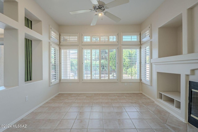 unfurnished sunroom featuring ceiling fan and a wealth of natural light