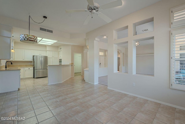 kitchen featuring white cabinetry, sink, ceiling fan, stainless steel fridge, and light tile patterned floors