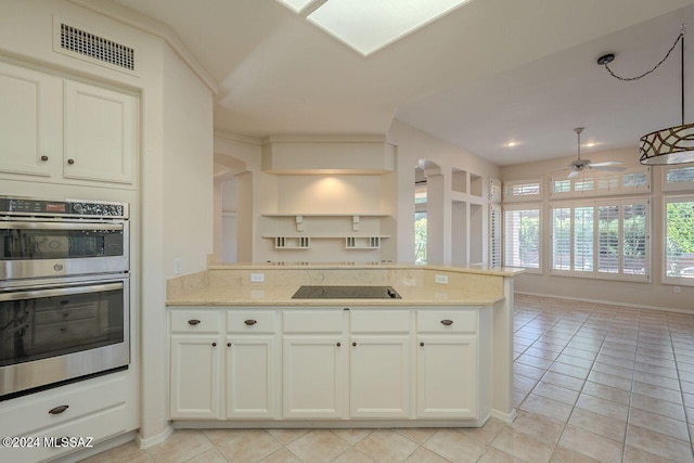 kitchen featuring ceiling fan, a wealth of natural light, light tile patterned floors, and double oven