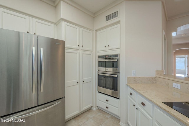 kitchen featuring white cabinetry, light stone countertops, light tile patterned floors, and appliances with stainless steel finishes