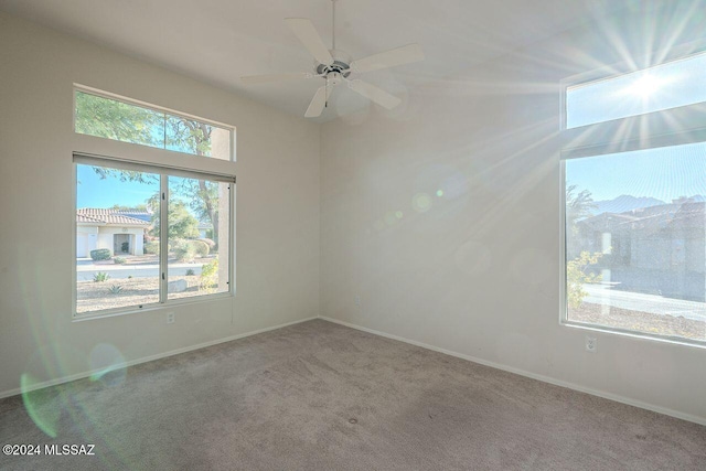 carpeted spare room featuring ceiling fan and a healthy amount of sunlight