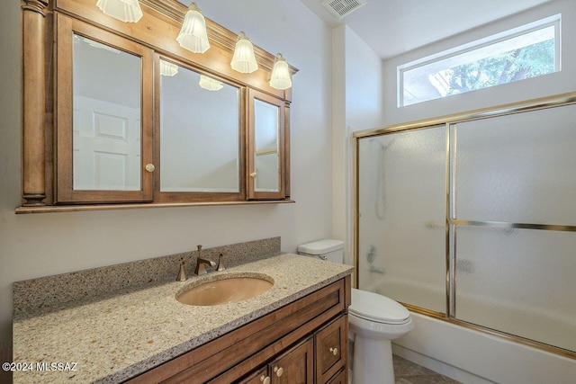 full bathroom with combined bath / shower with glass door, vanity, tile patterned flooring, and toilet