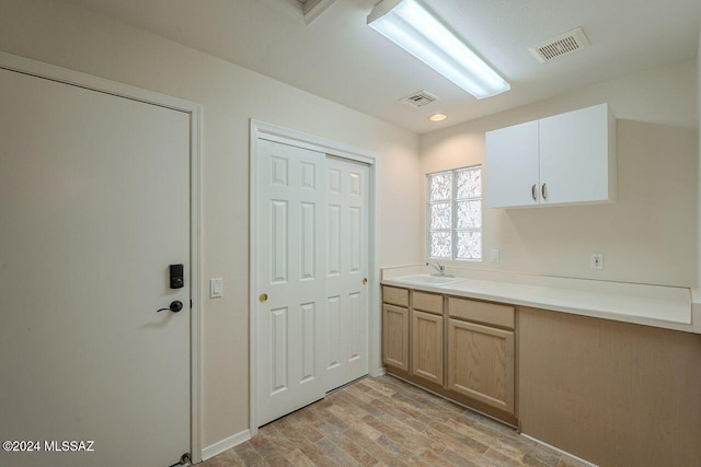 kitchen featuring light brown cabinets, light wood-type flooring, and sink