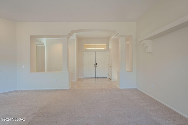 entrance foyer with ornate columns and light colored carpet