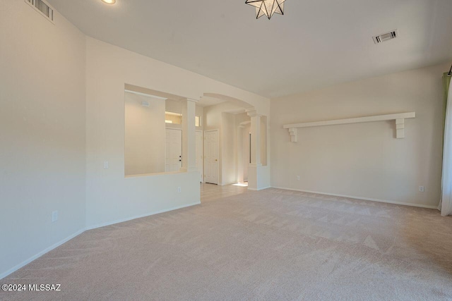 spare room featuring ornate columns and light colored carpet