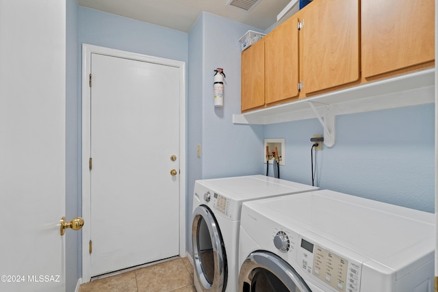 washroom with washing machine and clothes dryer, light tile patterned flooring, and cabinets