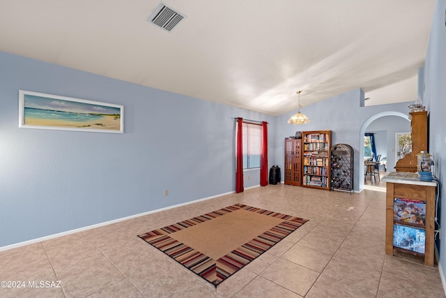 interior space featuring plenty of natural light, an inviting chandelier, light tile patterned flooring, and vaulted ceiling