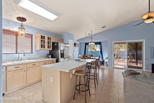 kitchen with sink, hanging light fixtures, stainless steel fridge, vaulted ceiling, and a kitchen island