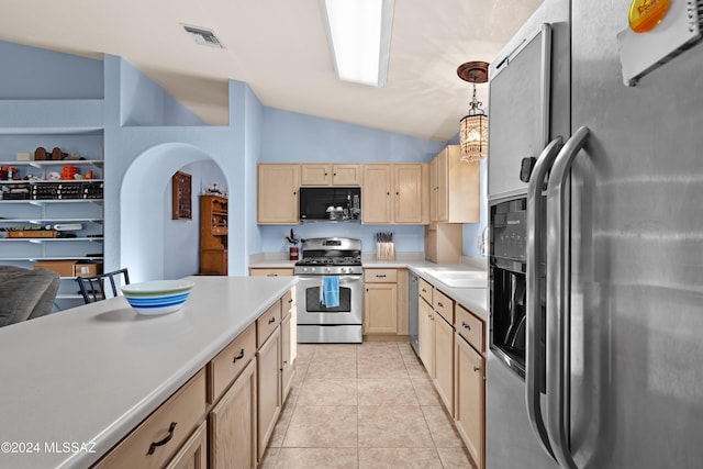 kitchen featuring vaulted ceiling, light tile patterned floors, light brown cabinetry, appliances with stainless steel finishes, and decorative light fixtures