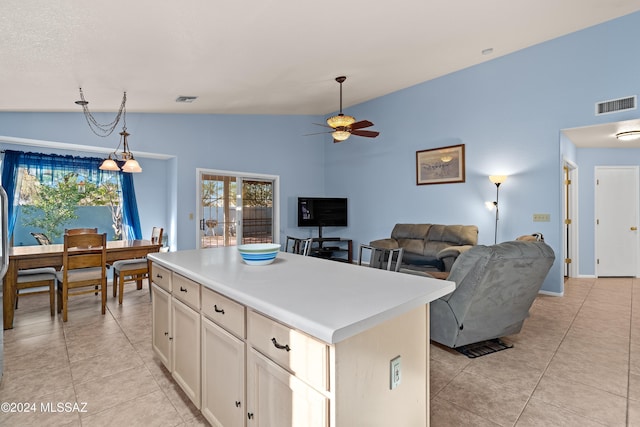 kitchen featuring ceiling fan with notable chandelier, decorative light fixtures, a center island, lofted ceiling, and light tile patterned flooring