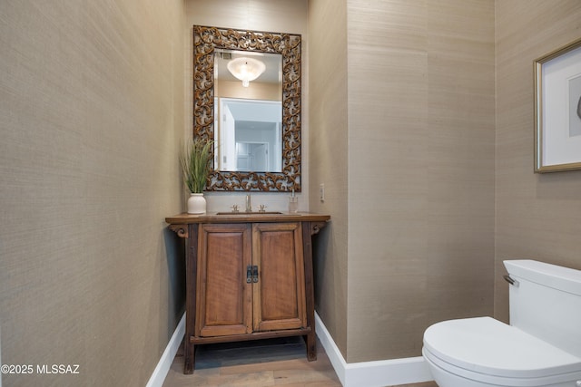 bathroom with toilet, vanity, and wood-type flooring