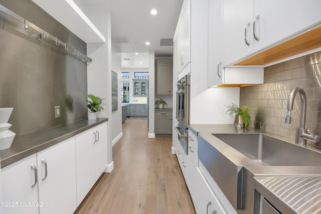 kitchen with light hardwood / wood-style floors, sink, white cabinets, and tasteful backsplash