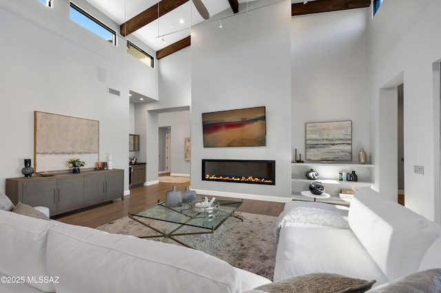 living room featuring beamed ceiling, a high ceiling, and hardwood / wood-style flooring