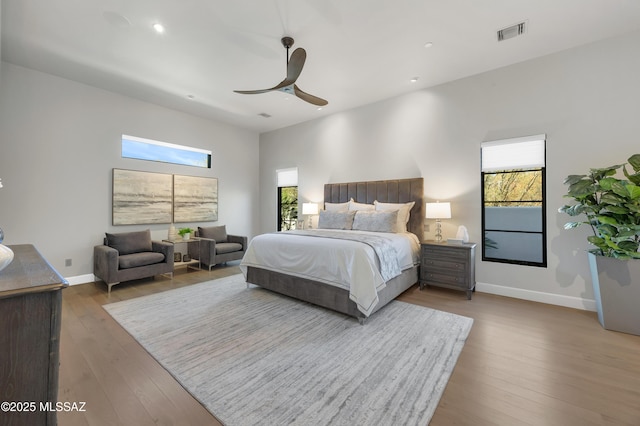 bedroom featuring ceiling fan, wood-type flooring, and multiple windows