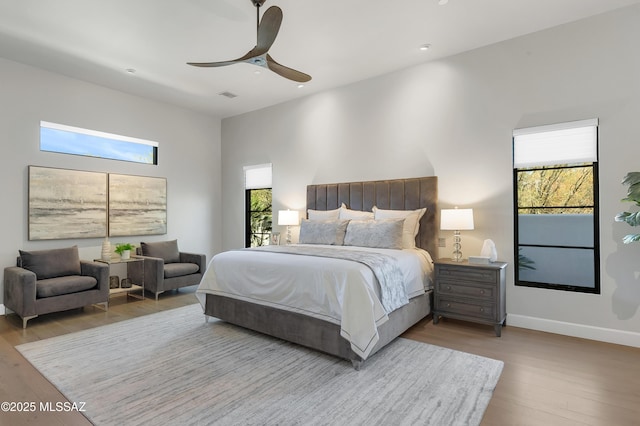 bedroom featuring ceiling fan, multiple windows, and light hardwood / wood-style flooring