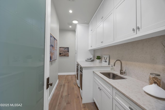 washroom with sink, washer and clothes dryer, and light hardwood / wood-style flooring