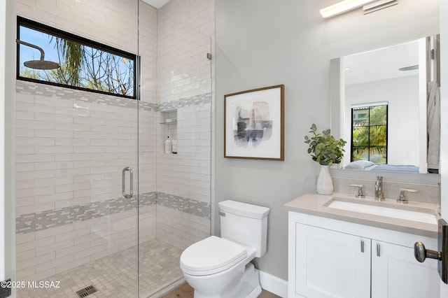 bathroom with toilet, an enclosed shower, and vanity