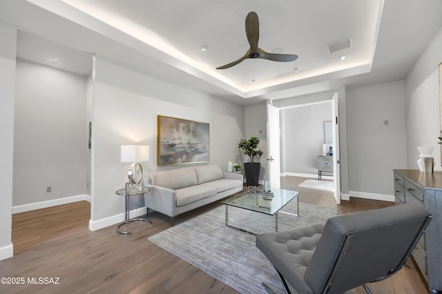 living room with ceiling fan, hardwood / wood-style floors, and a tray ceiling